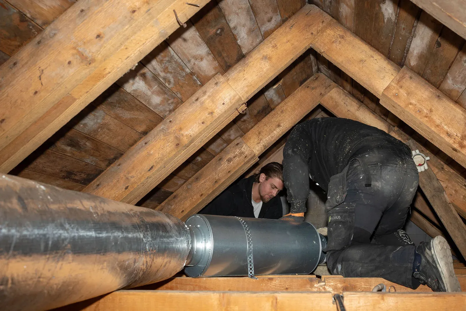 Tekniker från Aerius arbetar med ventilationskanaler mellan takstolarna vid ett aggregatbyte