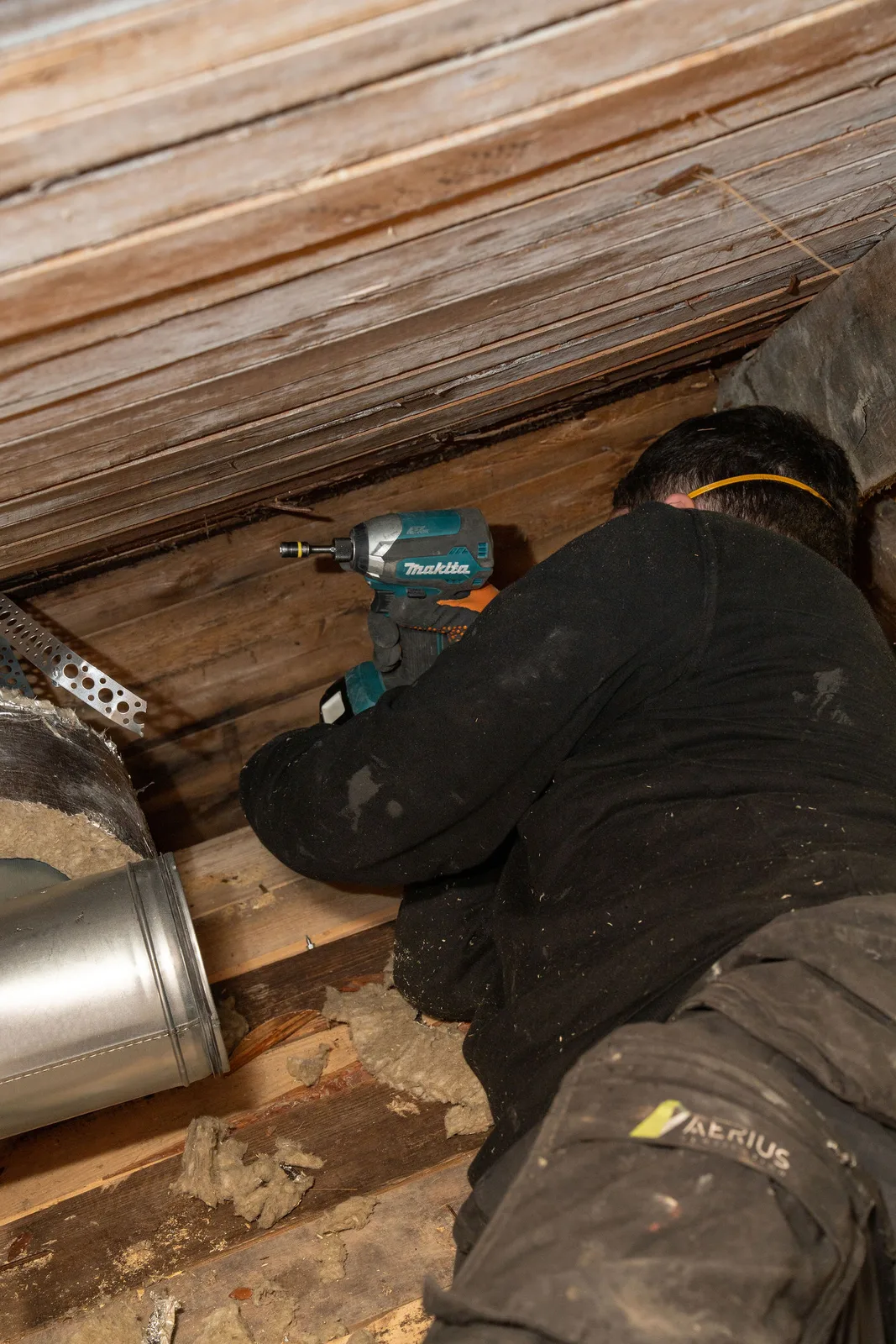 Montör kopplar ihop spirokanaler mellan takstolarna på en vind under FTX-installation i Skurup