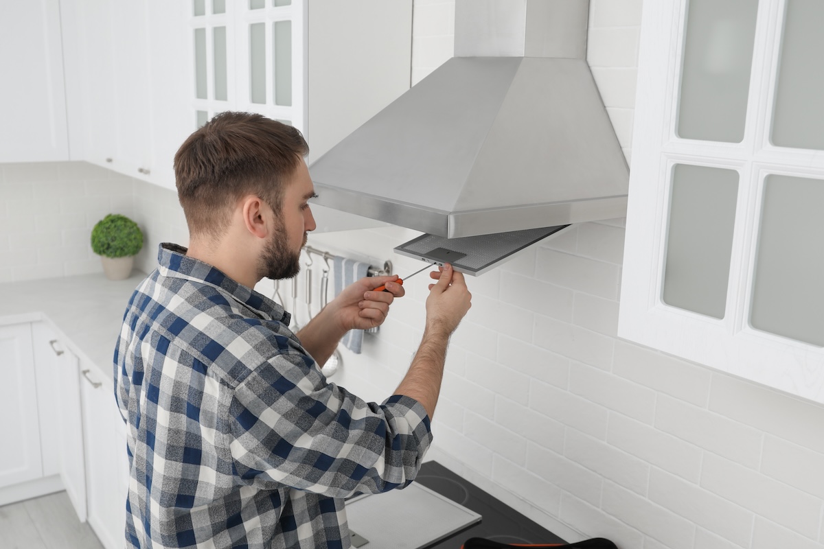 man installerar ny köksfläkt i hus