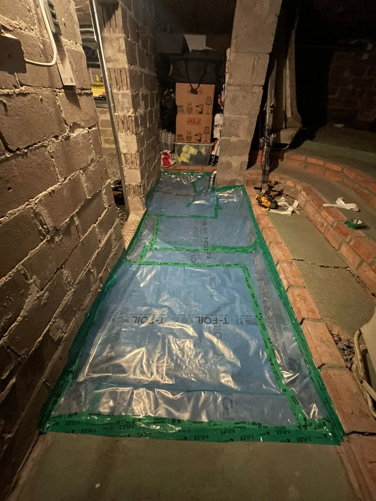 Plastduk tejpad mot väggarna på ett källargolv som spärr mot markradon